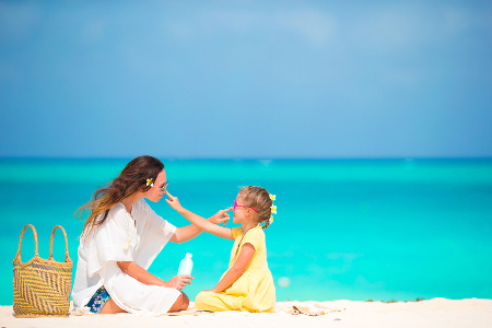 Little daughter applying sun cream to her mother nose